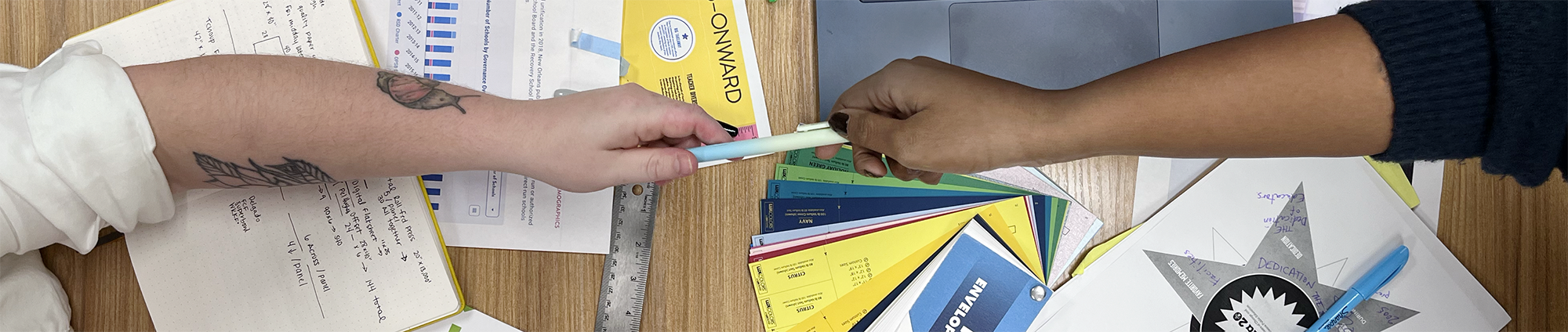 Arms reaching across a table, collaborating on creative process